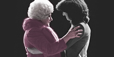 Mary Kay Ash faces a member of the Independent Sales Force in conversation with her hands on the woman’s shoulders.