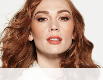 A smiling woman is wearing a Mary Kay makeup artist look that incorporates a hint of color and metallic neutrals to make skin appear sun-kissed for summer. 