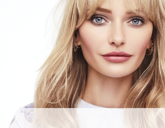 A smiling woman is wearing a Mary Kay makeup artist look that incorporates a hint of color and metallic neutrals to make skin appear sun-kissed for summer. 