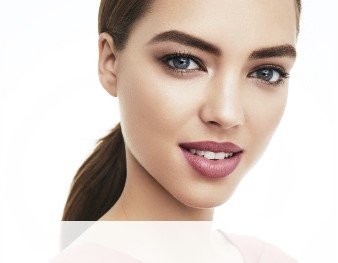 A smiling woman is wearing a Mary Kay makeup artist look that incorporates a hint of color and metallic neutrals to make skin appear sun-kissed for summer. 